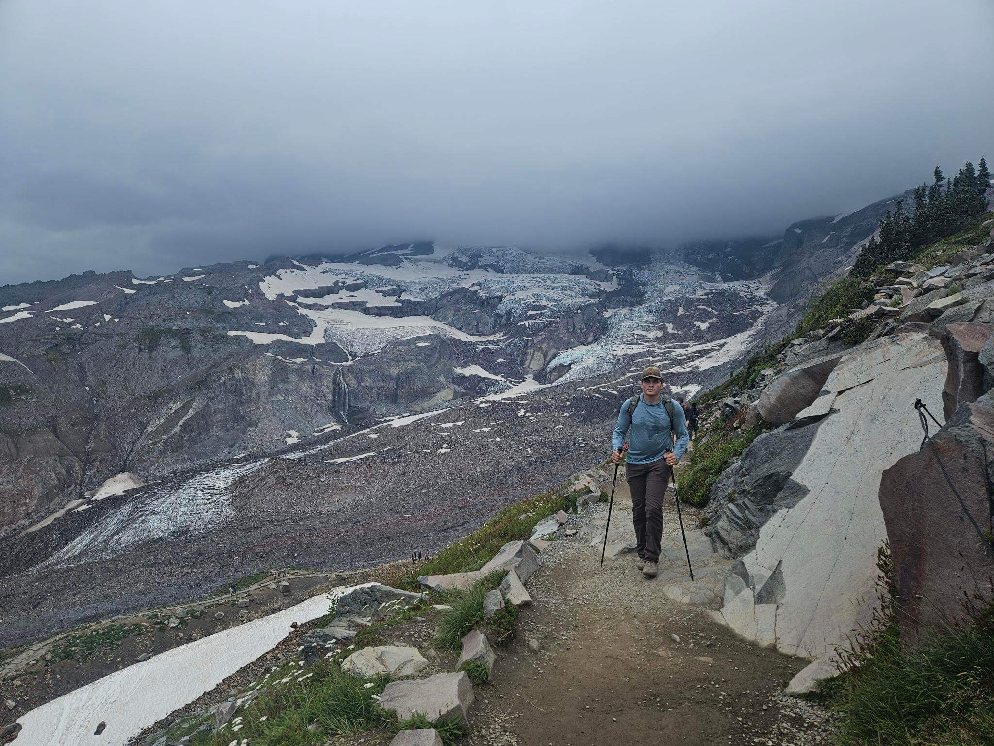 Zayne backpacking on Mount Rainier with a full pack and trekking poles in 2023