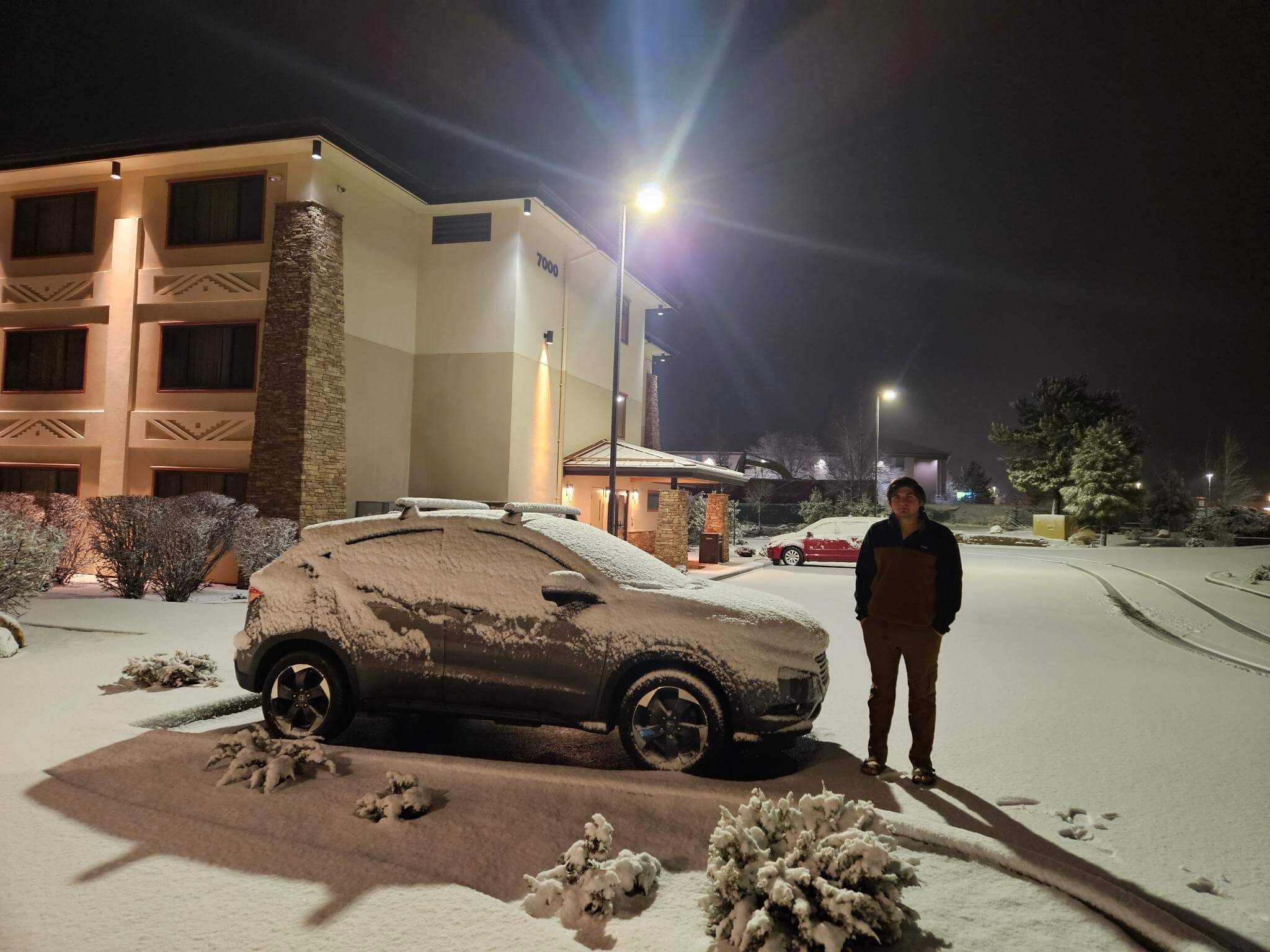 Zayne standing beside his car in the snow outside the Grand Canyon before beginning his backpacking journey