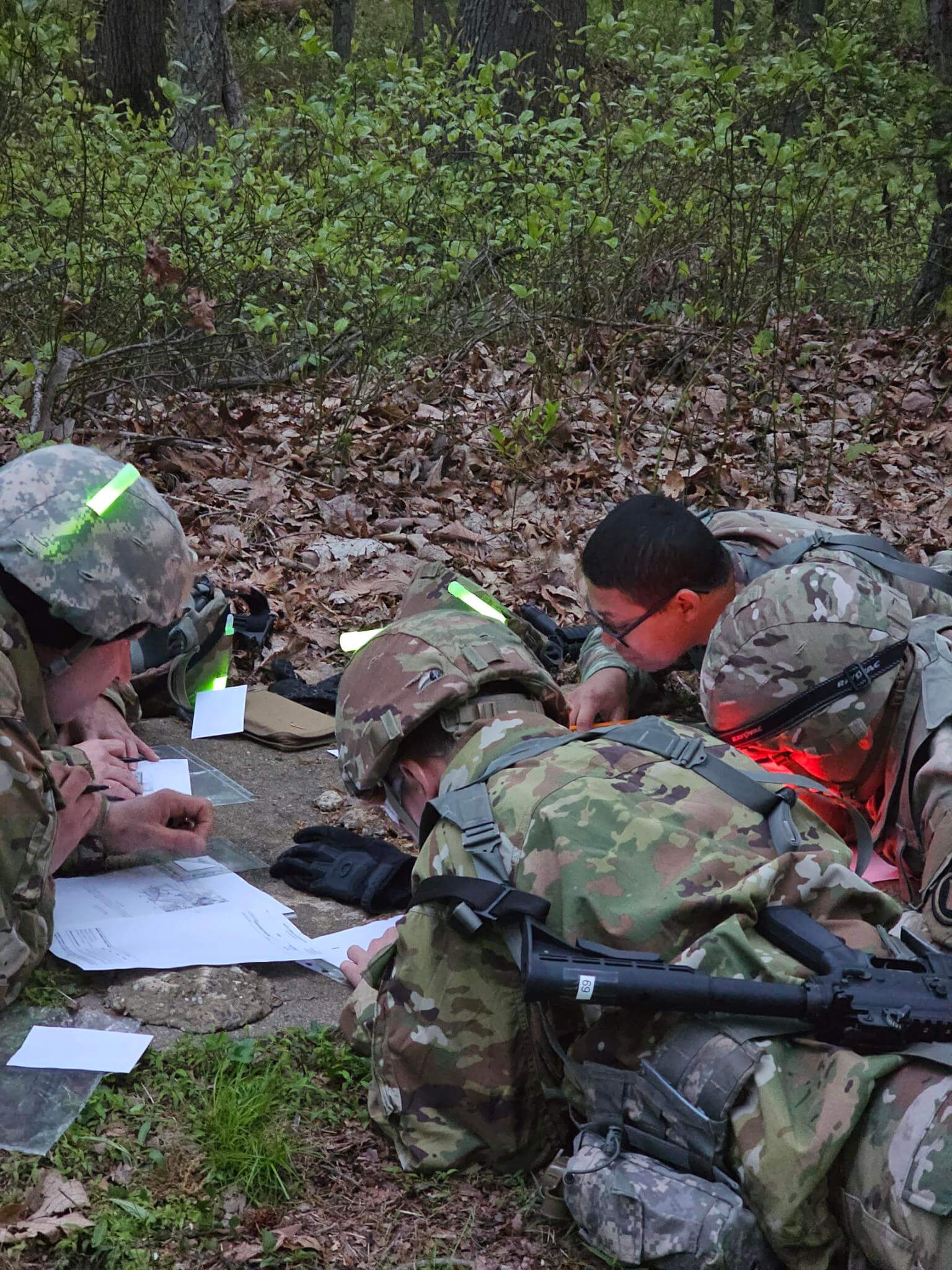 U.S. Army soldiers navigating through forest terrain during a land navigation exercise.