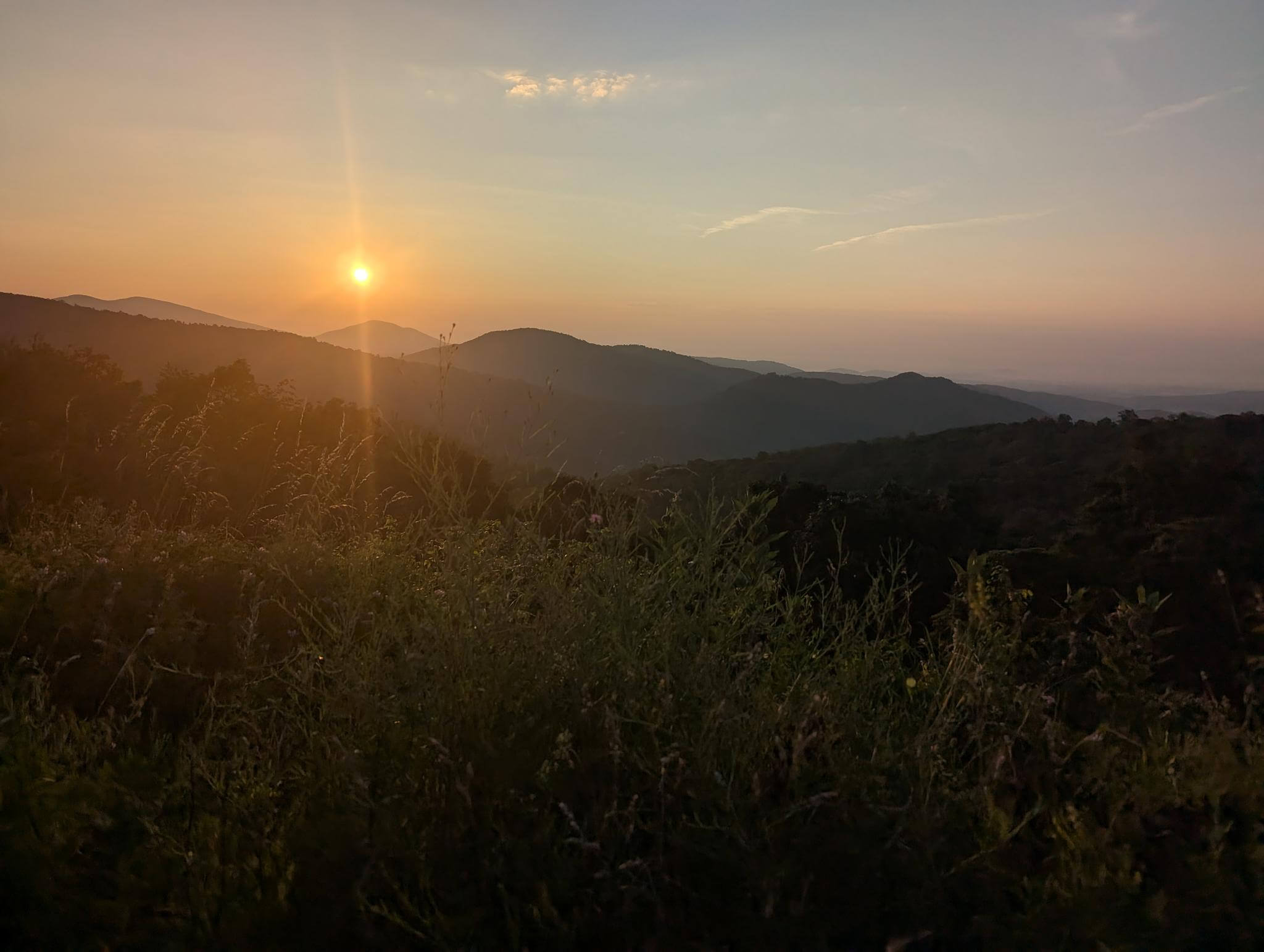 Sunrise in Shenandoah National Park — warm light breaking over the ridges with morning mist in the valleys.